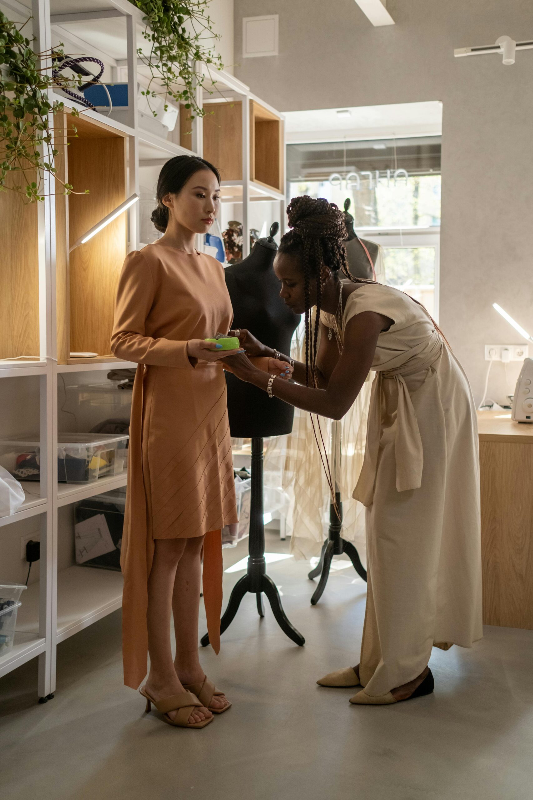 A fashion designer adjusting a dress on a client in a modern atelier.